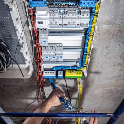 male-electrician-works-switchboard-with-electrical-connecting-cable 1